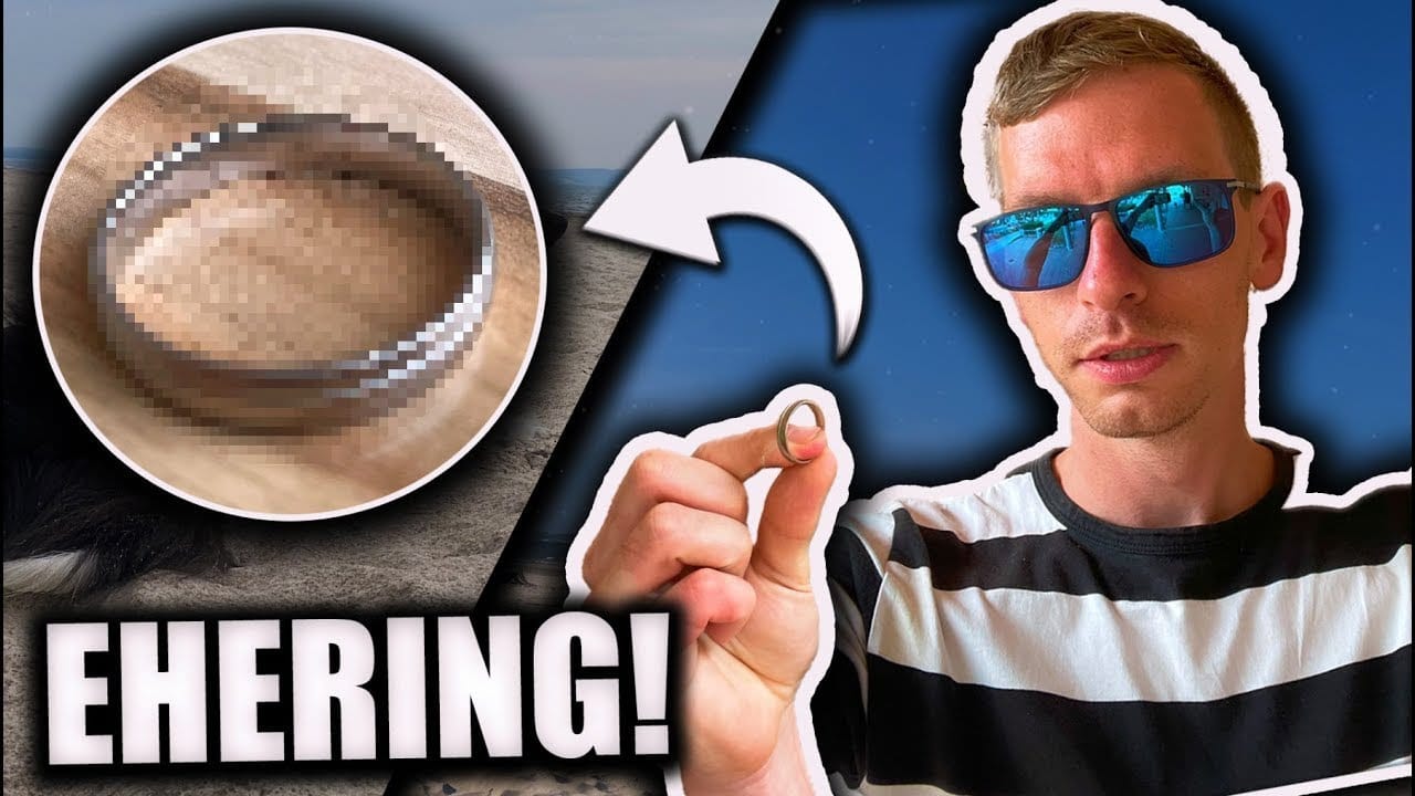 Ein Mann mit Sonnenbrille und gestreiftem Hemd hält einen Ring in der Hand - perfekt für jedes Schatzsuche Metalldetektor-Abenteuer. Neben ihm ist ein verpixelter Ring mit einem fetten weißen Pfeil und der Aufschrift "EHERRING!" zu sehen.