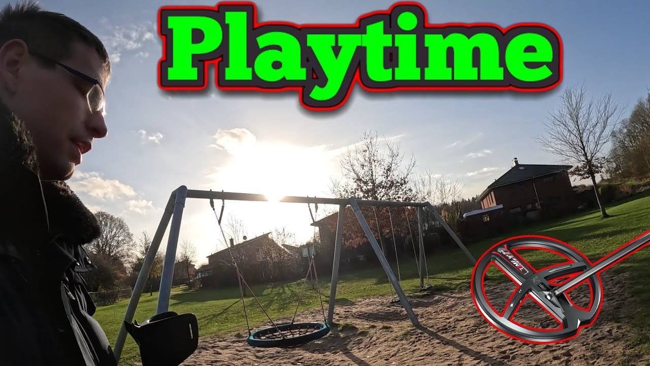 Eine Person steht in der Nähe einer leeren Schaukel auf einem Spielplatz bei Sonnenuntergang. Oben steht in fetter grüner und roter Schrift "Playtime" (Spielzeit), rechts ist eine Spulengrafik "Schatzsuche metalldetektor" eingeblendet, die auf versteckte Schätze hinweist, die es zu finden gilt.