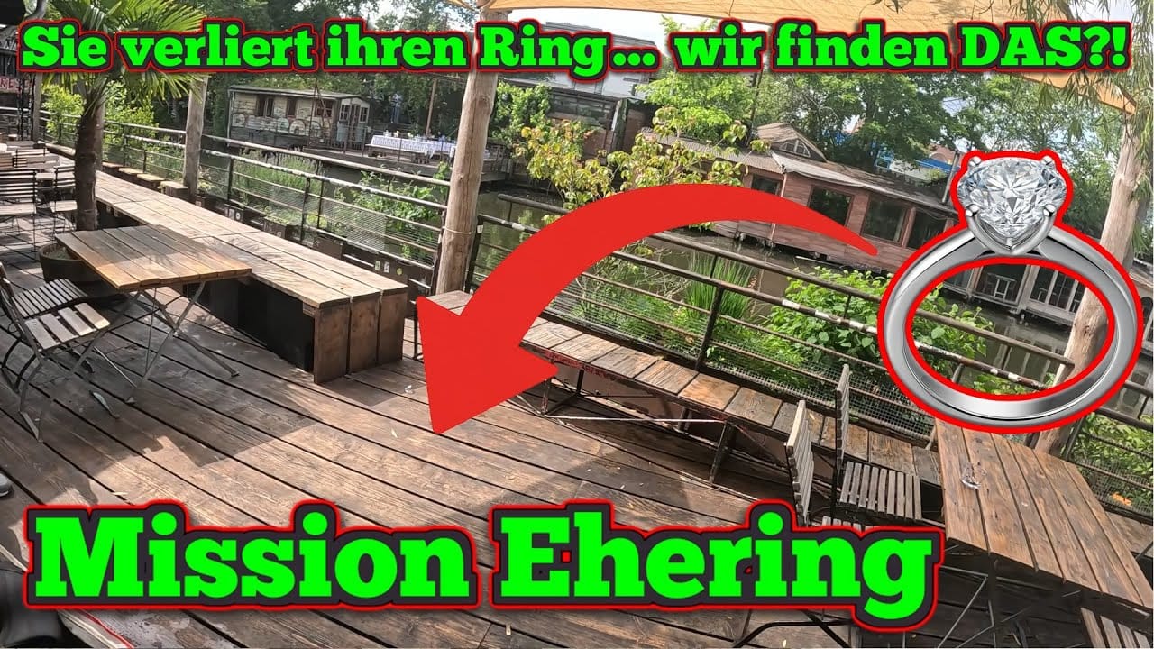 Ein großer roter Pfeil zeigt auf einen Diamantring auf dem Boden einer Holzterrasse. Der deutsche Text lautet Sie verliert ihren Ring ... wir finden DAS?! Mission Ehering in grün und gelb. Perfekt für Schatzsuche Metalldetektor-Fans und Geschichten von Ring verloren gefunden!.